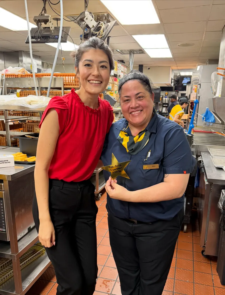 Two team members smiling with a gold star near the bakery shelves
