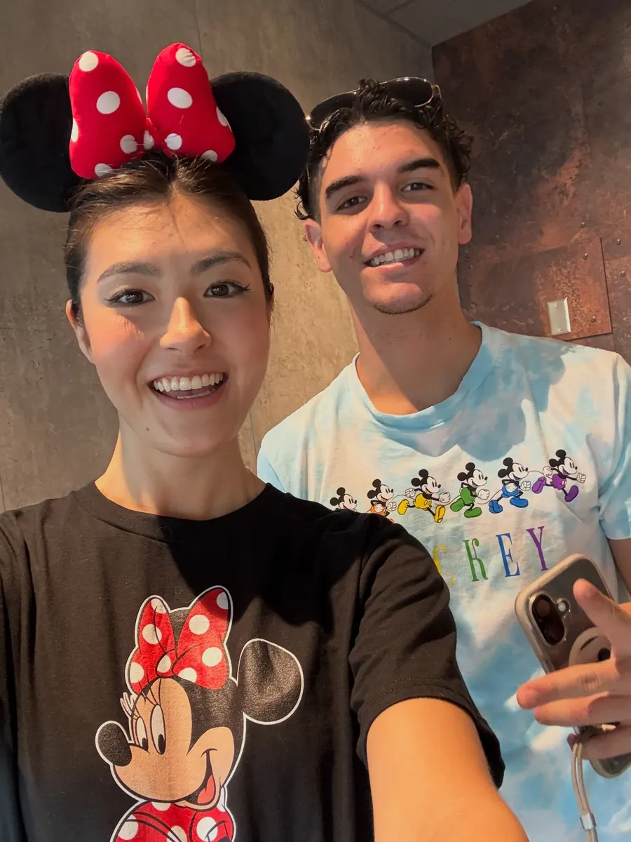 Two crew members taking a selfie in Minnie Mouse ears