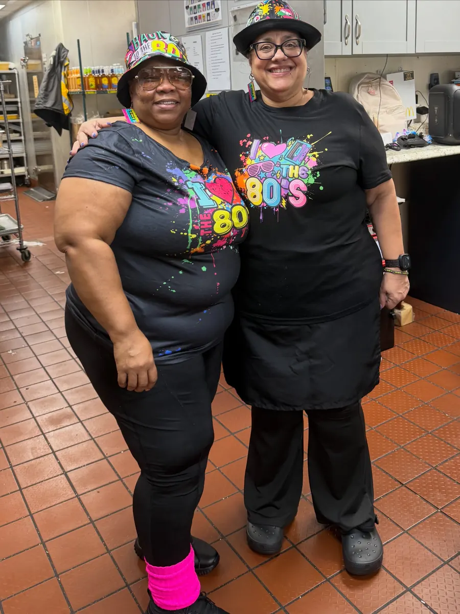 Two crew members in 80s shirts and hats for Throwback Thursday