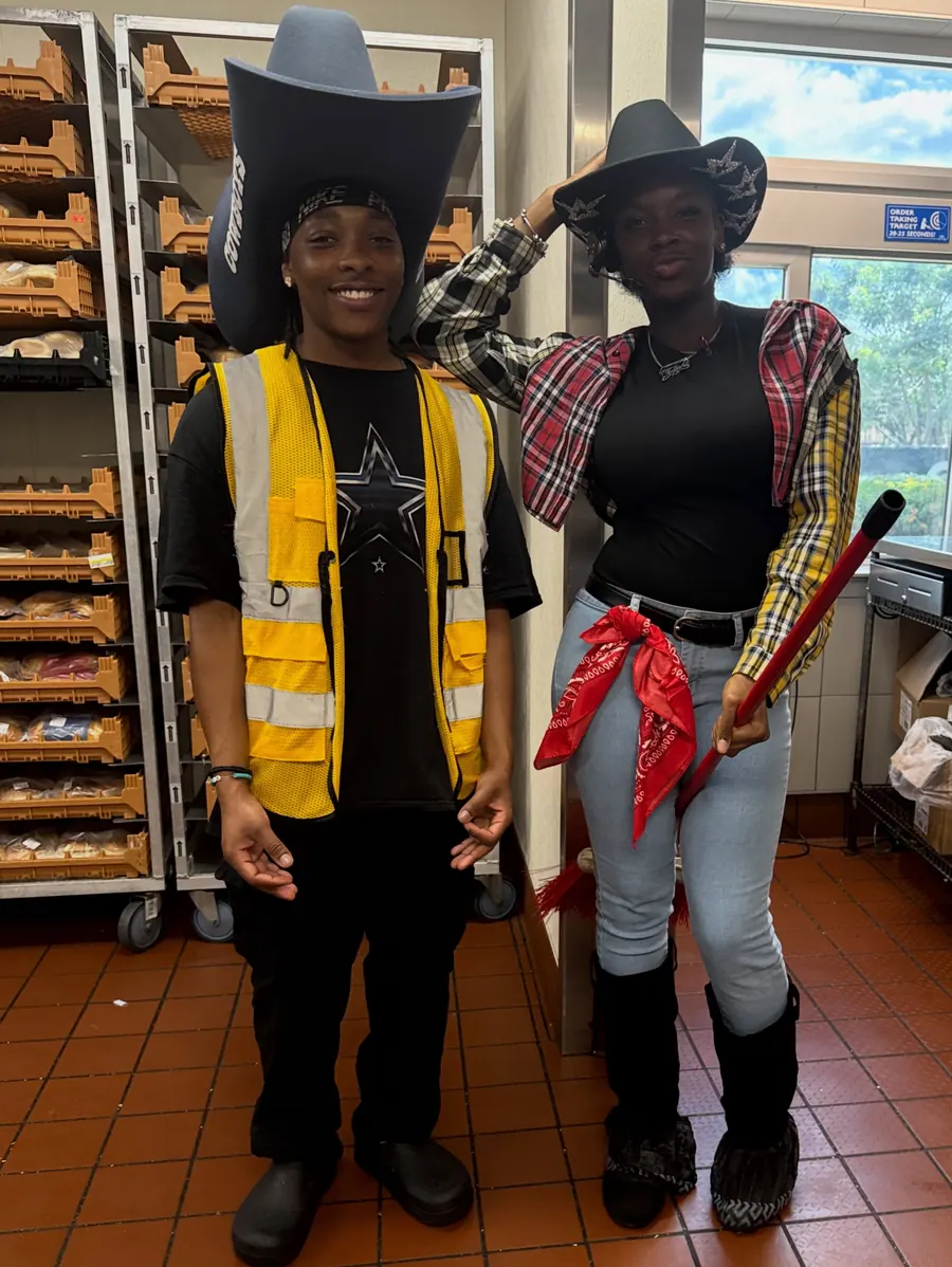 Two crew members in cowboy hats near the bakery racks